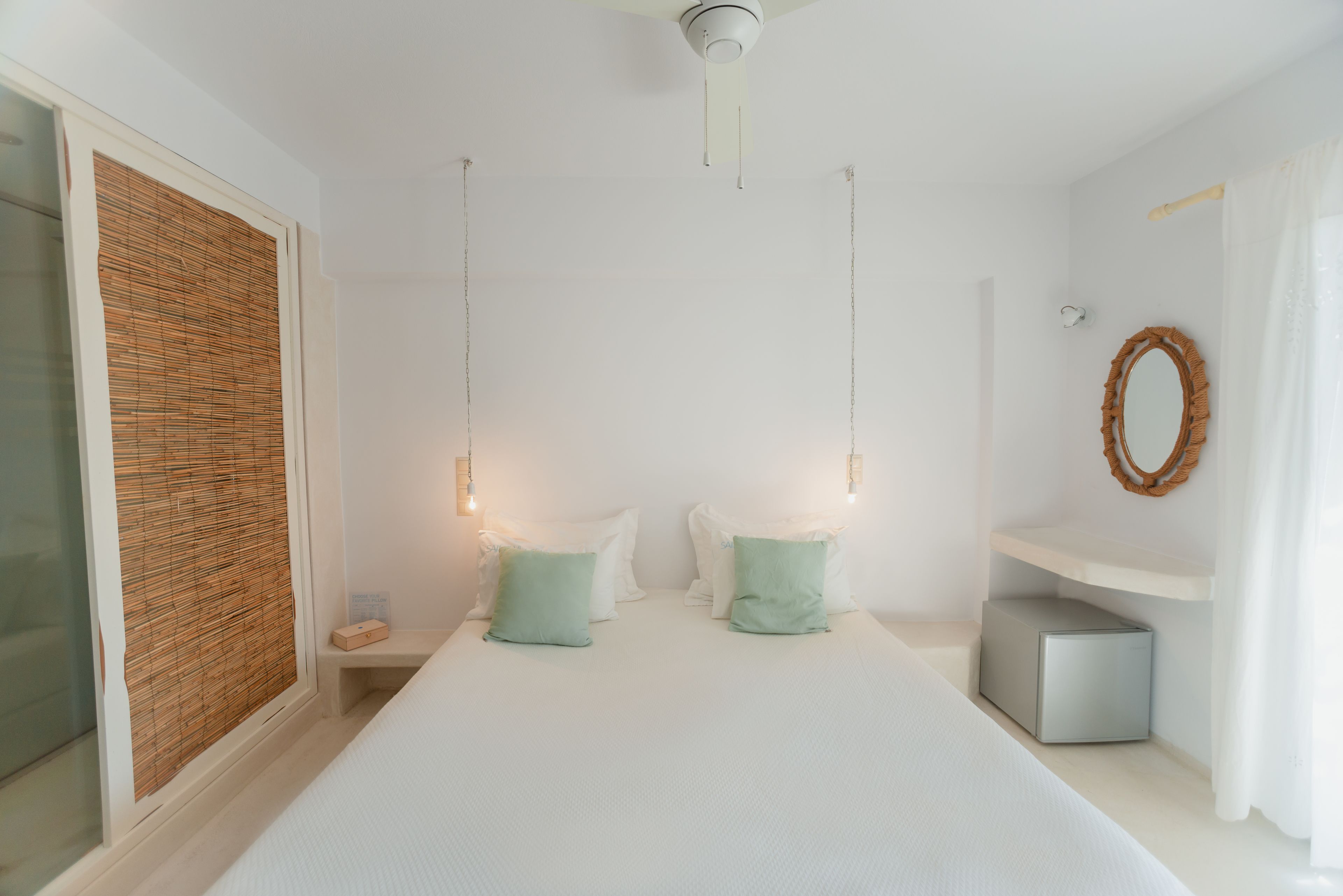 A bedroom with a bed, bedside tables, a mirror, and a ceiling fan.