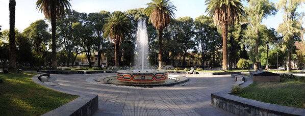 A fountain in a circular plaza surrounded by palm trees and benches. - Crillon Mendoza (Mendoza)
