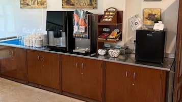 A coffee station with a coffee machine, a milk frother, and a yogurt dispenser.