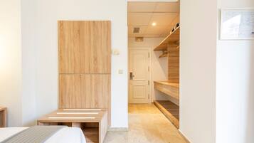 Una habitación de hotel moderna con cabecera de madera, cama con cubrecama a rayas, banco de madera y estante de madera.