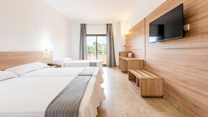 Une chambre d’hôtel avec deux lits, un téléviseur fixé au mur, une étagère en bois et une vue sur l’extérieur grâce à une grande fenêtre.