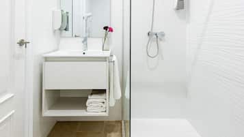 A modern bathroom with a glass-enclosed shower, a white sink with a mirror, and a towel rack.