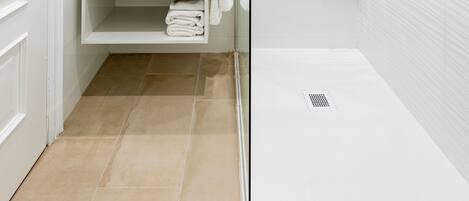Un baño moderno con ducha de vidrio, lavamanos blanco y un perchero para toallas.