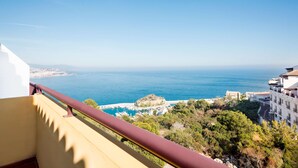 Un balcon avec vue sur la mer, une petite île et les bâtiments environnants.