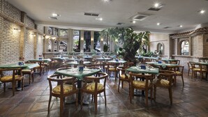 Un vaste espace dédié à la salle à manger, avec des murs en briques, des tables et des chaises en bois.