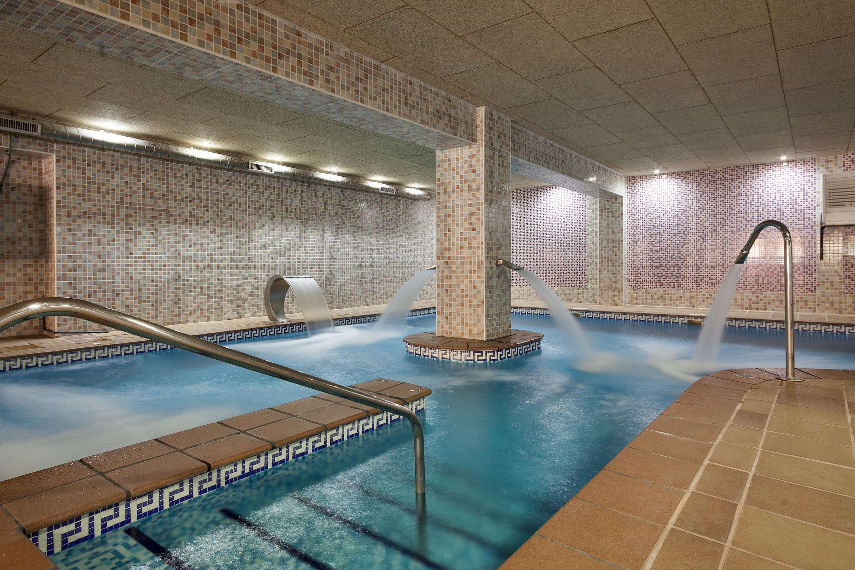 Une piscine aux murs recouverts de carreaux et dotée d’une fontaine.