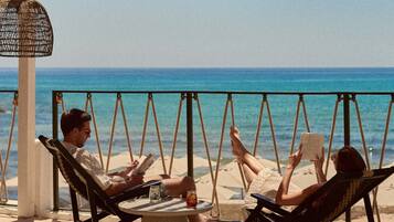 A beachside setting with a swing chair, a round table, and a thatched umbrella.