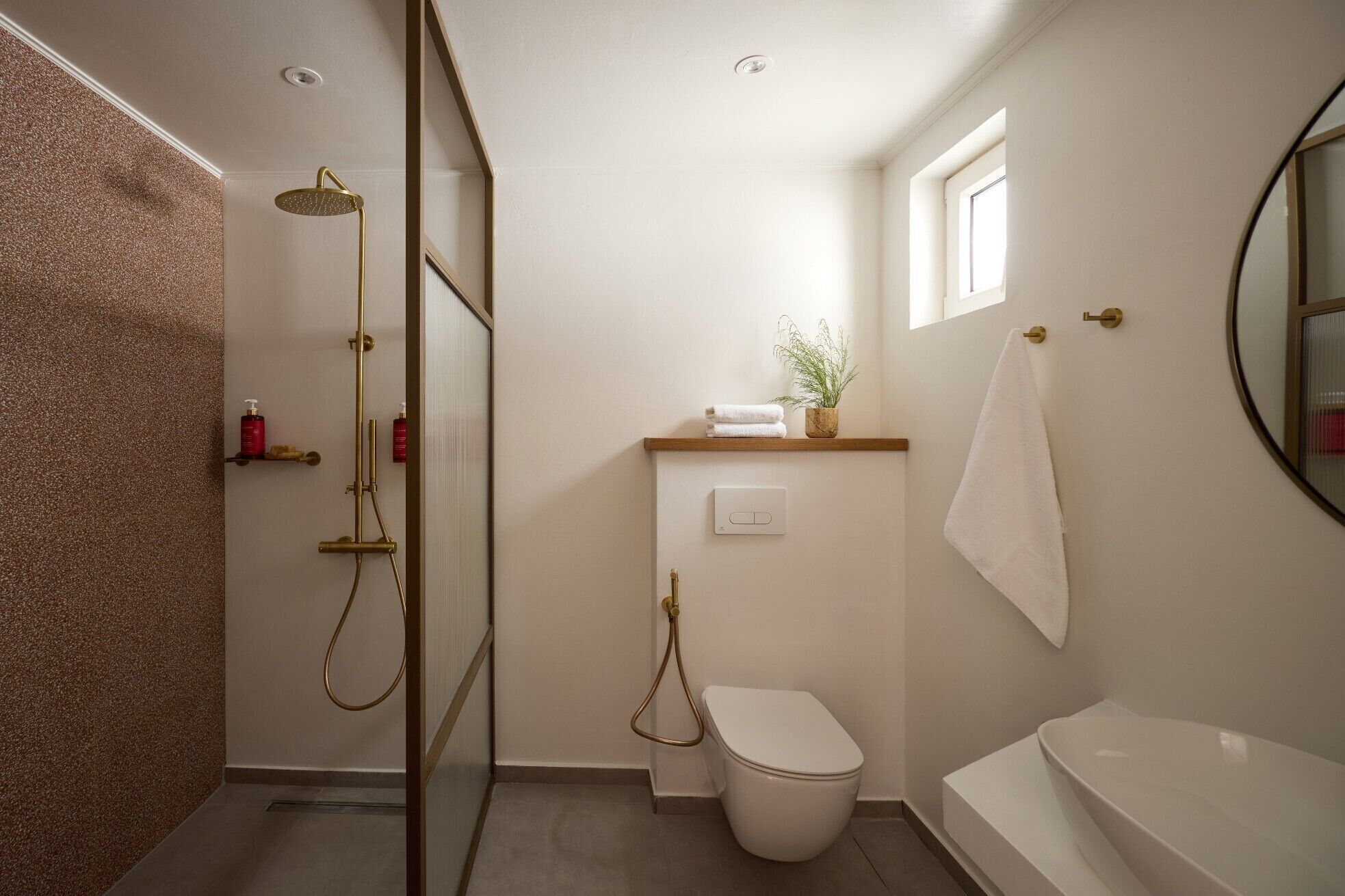 A bathroom with a shower, toilet, and bathtub, a towel rack, and a small window.