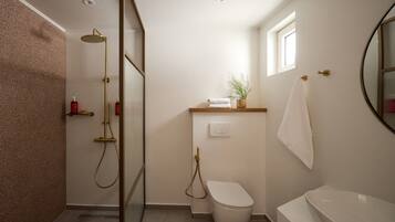 A bathroom with a shower, toilet, and bathtub, a towel rack, and a small window.