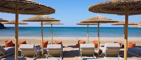 Een privéstrand, wit zand, ligstoelen aan het strand, parasols