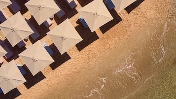 Aan een privéstrand, wit zand, ligstoelen, parasols