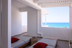 Ein Zimmer mit zwei Betten und Blick aufs Meer, mit weißer Decke.