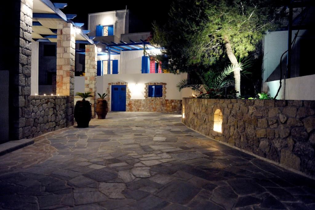 A stone-paved courtyard with a building featuring blue doors and a stone wall.