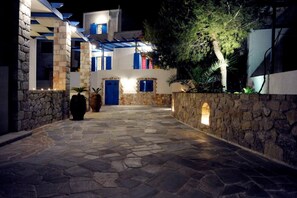 A stone-paved courtyard with a building featuring blue doors and a stone wall.