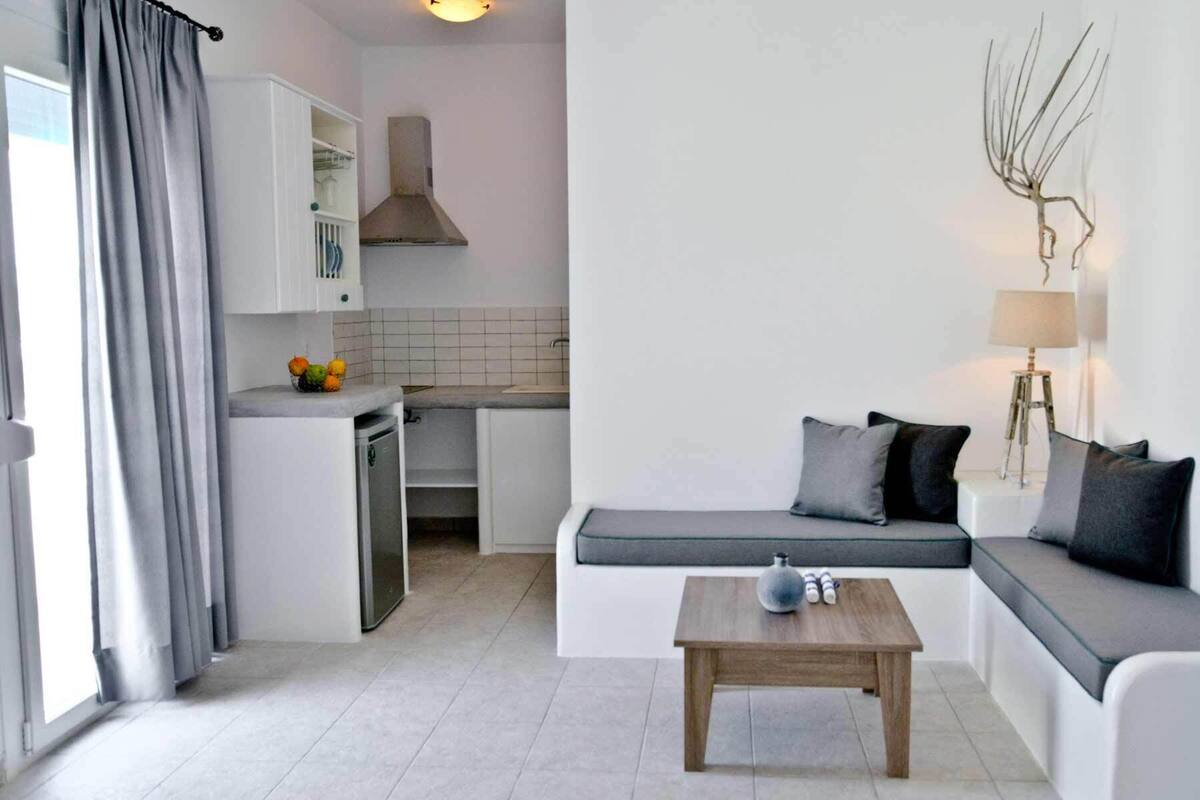 A modern living room with a sofa, a coffee table, and a kitchen in the background.