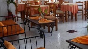 A dining area with multiple tables and chairs, a sofa, and potted plants. - Anezina (Milos)