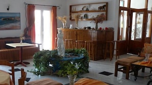 A dining area with a wooden bar, a statue centerpiece, and a painting on the wall. - Anezina (Milos)