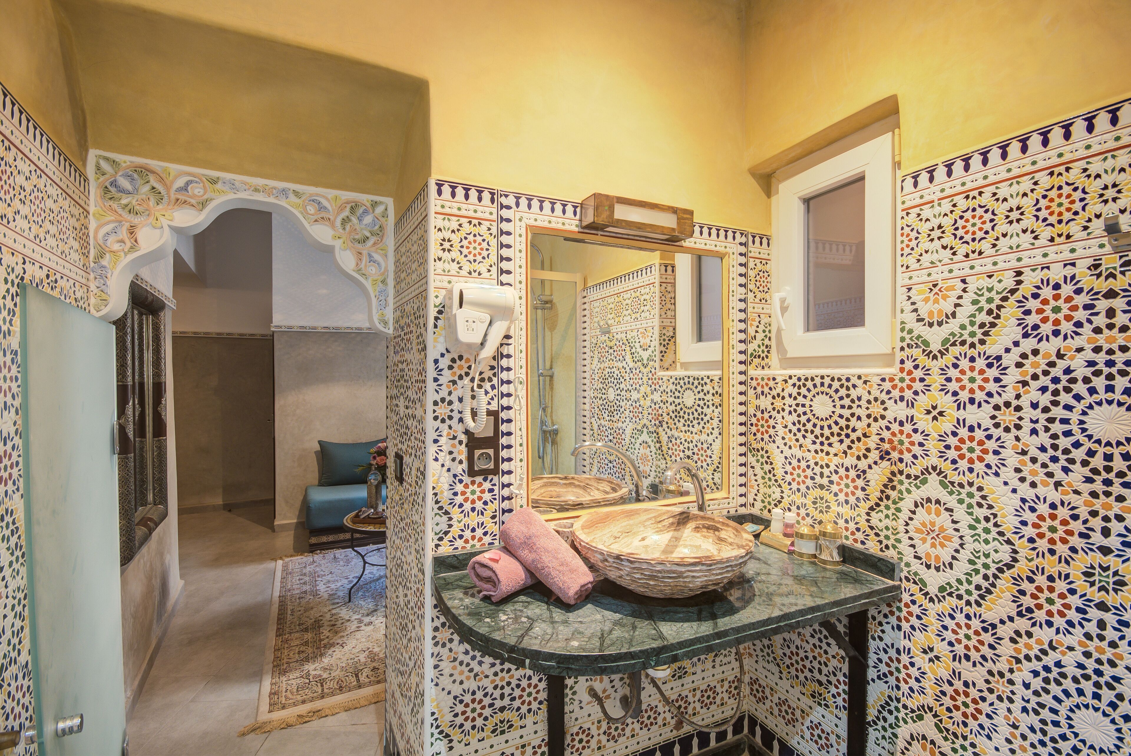 Een badkamer met een betegelde mozaïekmuur, een rond wastafel en een handdoek op het aanrecht.