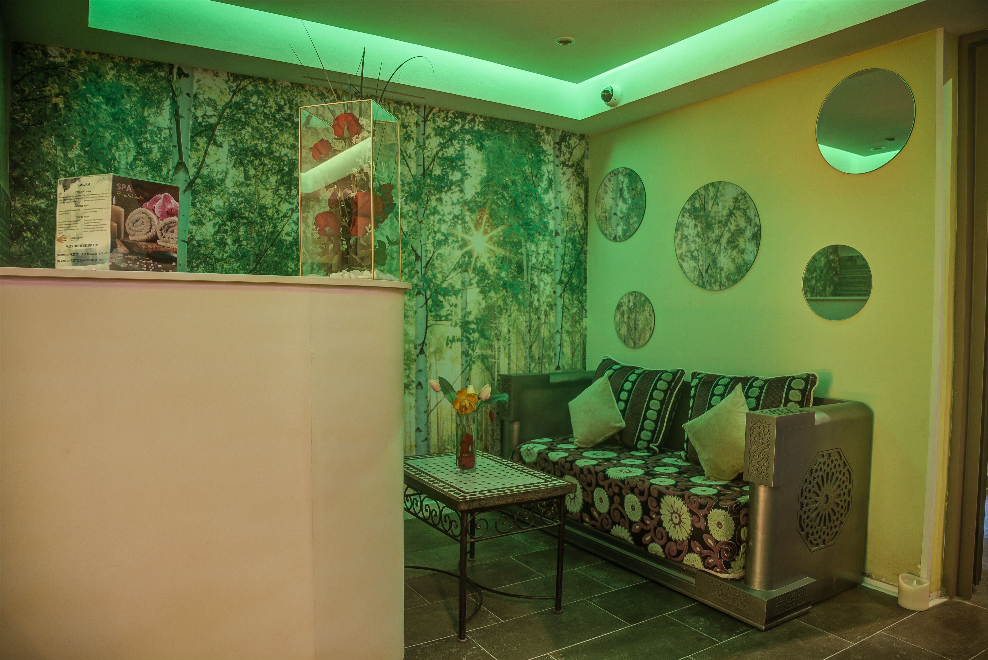 Una sala de estar con un sofá, una mesa con un florero y una pared con espejos circulares y un mural.
