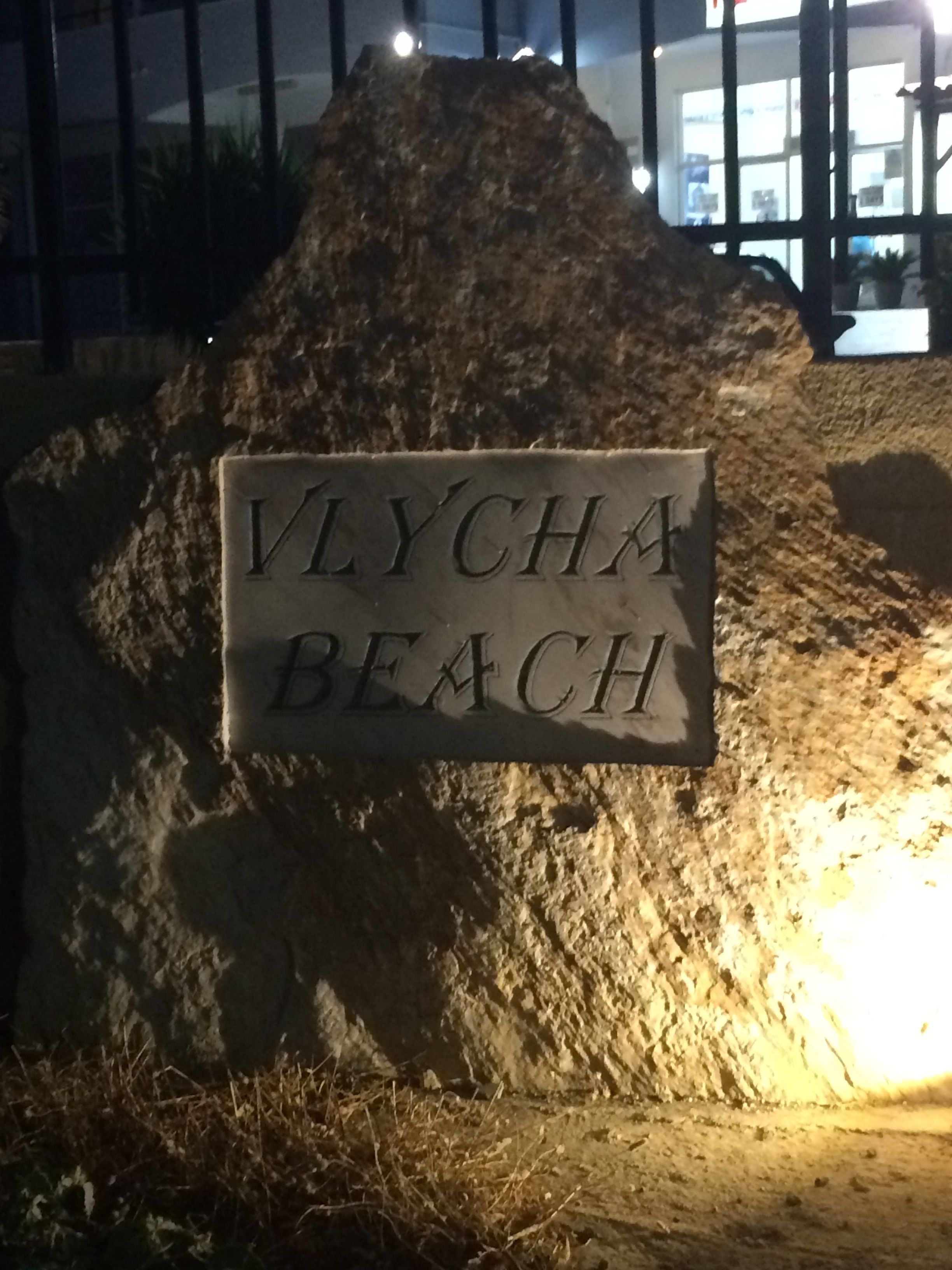 En skylt med texten ”Vlycha Beach” på en stenkonstruktion.