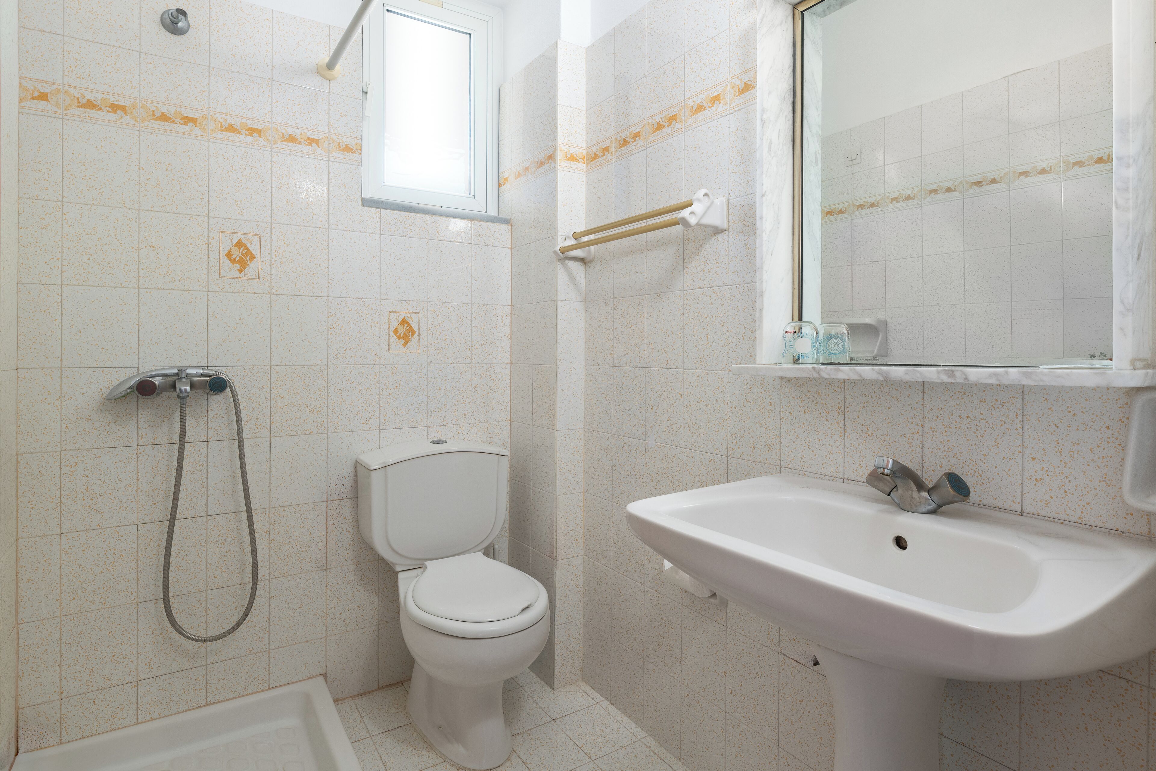 A bathroom with a toilet, a sink, a shower, and a window.