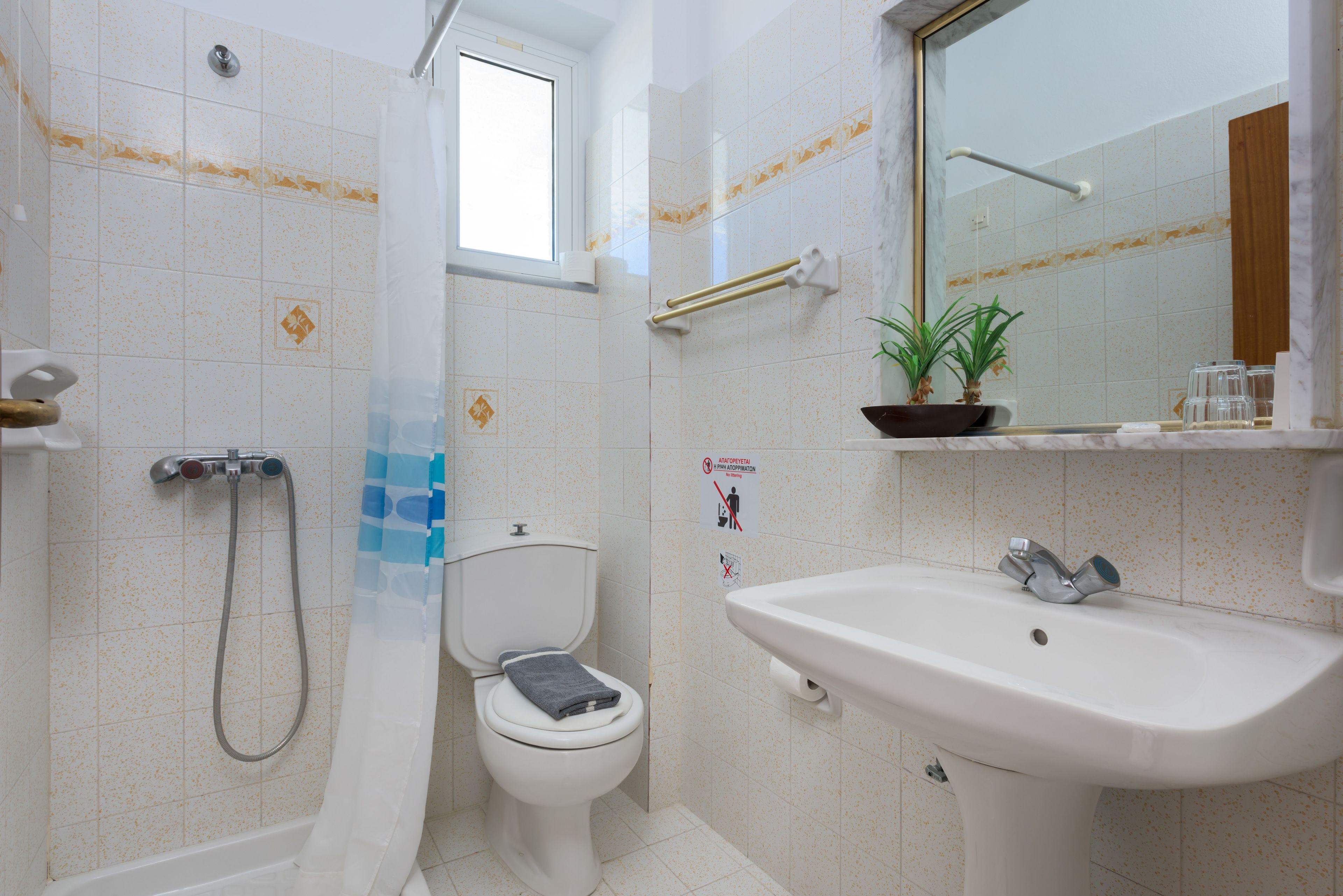 Et badeværelse med toilet, brusebad, vask og et vindue.