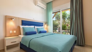 A bedroom with a bed, nightstands, a window with curtains, and an air conditioning unit. - Vlycha Beach Studios & Apartments (Rhodes)