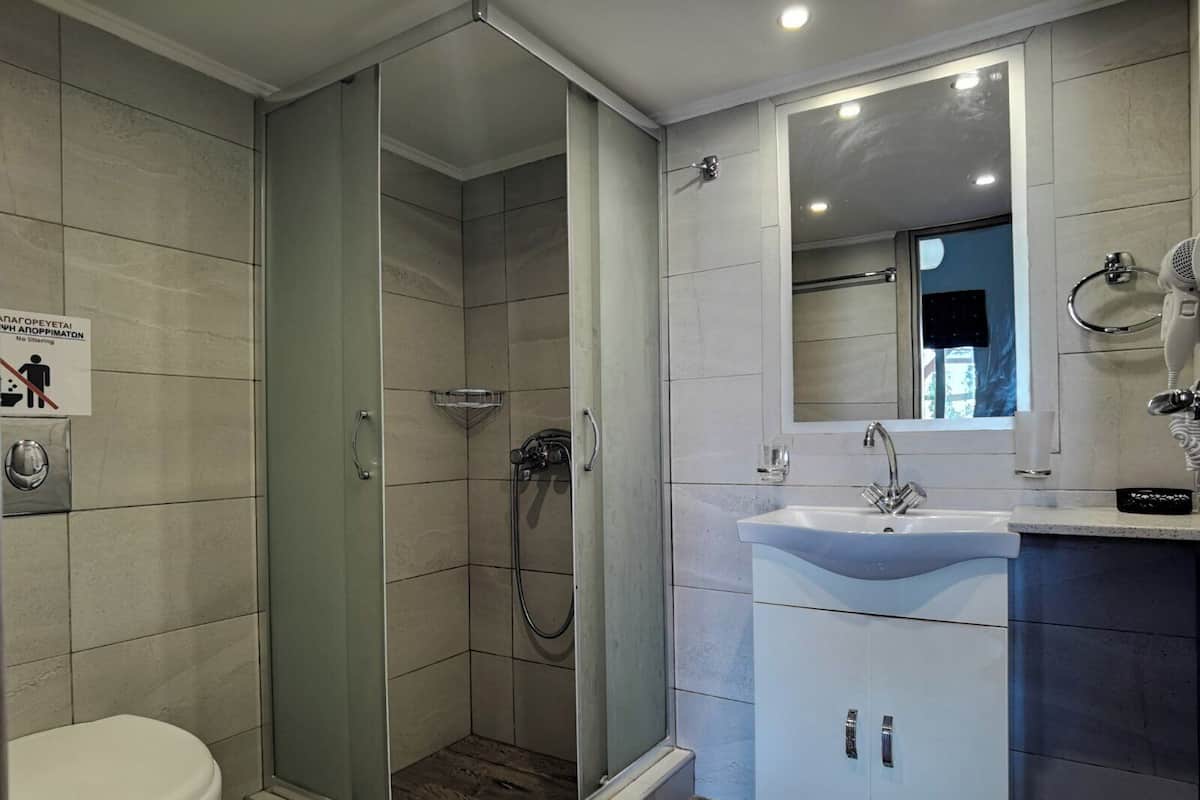 Un baño moderno con ducha de vidrio, un lavamanos blanco y un inodoro.