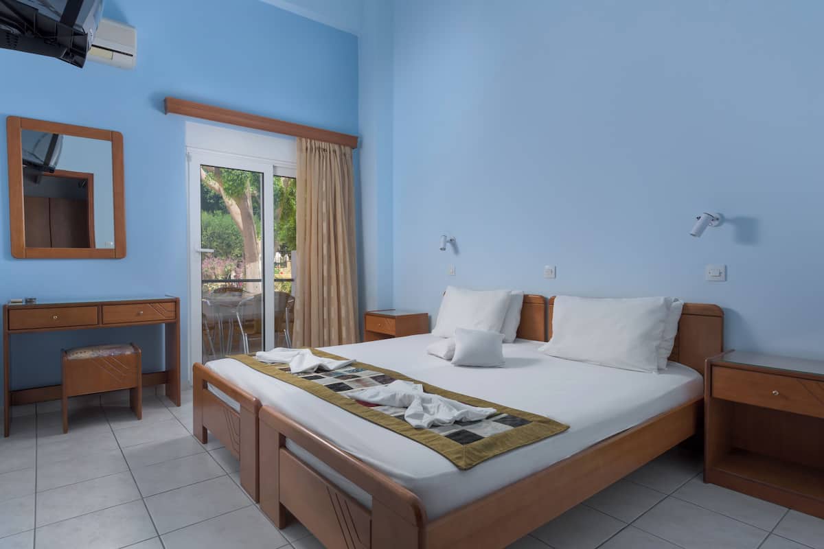 Une chambre à coucher avec un lit, un bureau, une chaise, une armoire et une fenêtre avec des rideaux.