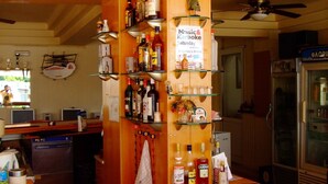 A bar area with a clock, shelves of bottles, a sign for Music & Karaoke, and a refrigerator. - Antonios Hotel (Rhodes)