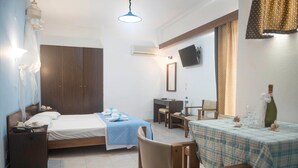 A hotel room with a bed, bedside table, desk, chair, and a dining table with a checkered tablecloth. - Antonios Hotel (Rhodes)