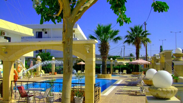 A poolside area with lounge chairs, a fountain, and a clear blue sky. - Antonios Hotel (Rhodes)