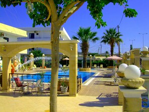A poolside area with lounge chairs, a fountain, and a clear blue sky. - Antonios Hotel (Rhodes)