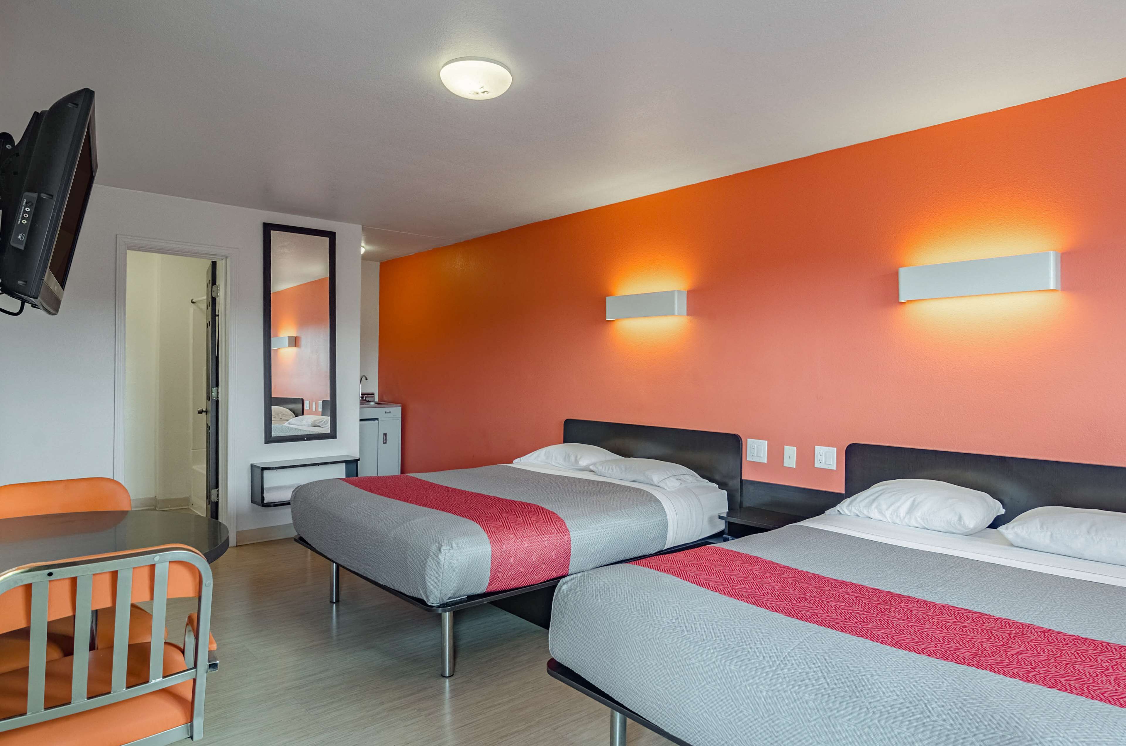 A hotel room with two beds, a TV, a desk, and a mirror.