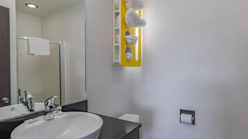A bathroom with a white sink, a mirror, a towel rack, and a toilet.
