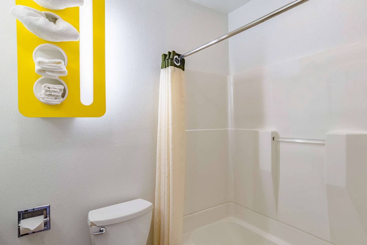 Ein Badezimmer mit Dusche, Toilette und einem Handtuchhalter mit gefalteten Handtüchern.