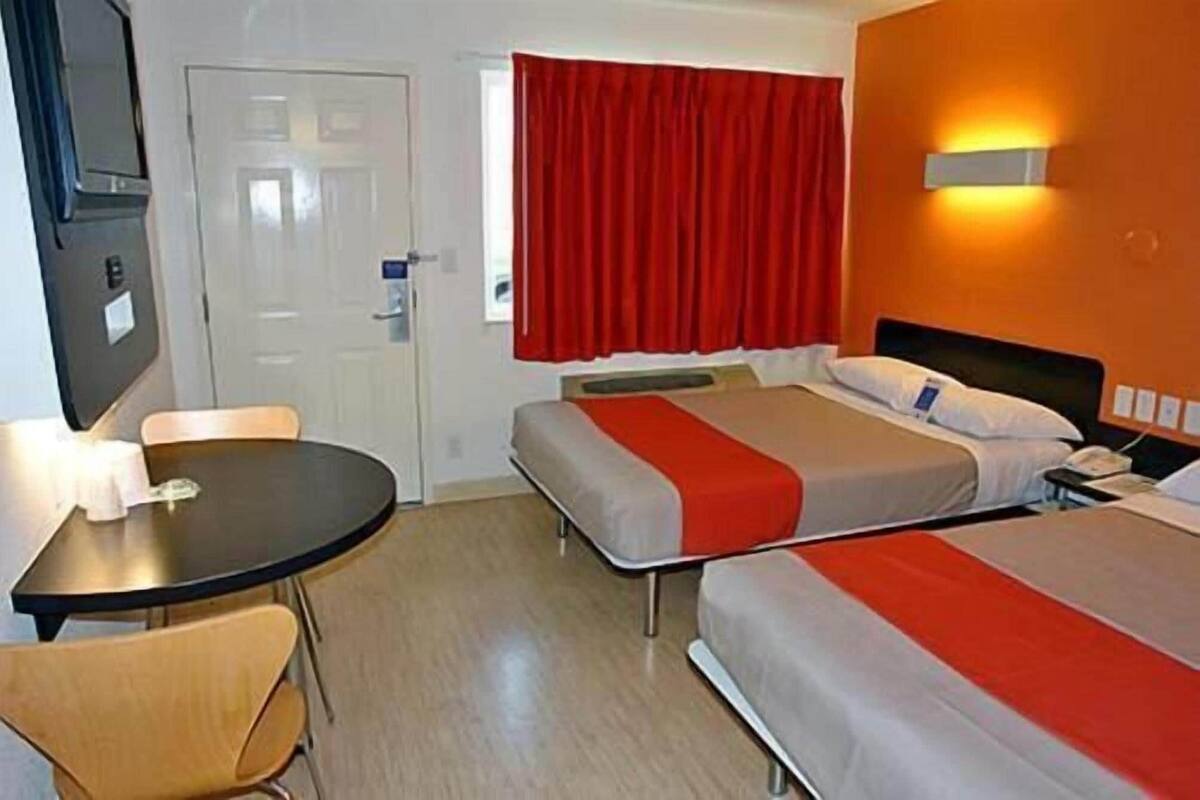 Ein Hotelzimmer mit zwei Betten, einem Schreibtisch und einem Stuhl.
