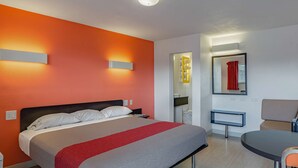 Ein modernes Hotelzimmer mit einem großen Bett, einem Schreibtisch und einem Sessel.