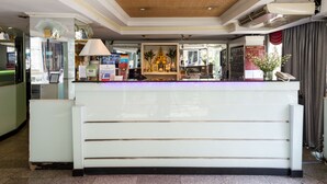 A reception desk with a modern design, a ceiling with recessed lighting, and a visible air conditioning unit.