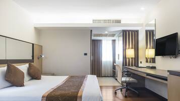 Une chambre d’hôtel équipée d’un lit, d’un bureau, d’une chaise et d’un téléviseur.