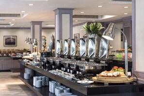 A buffet setup with multiple serving stations, a variety of dishes, and a decorative plant. - SC Park Hotel (Bangkok)