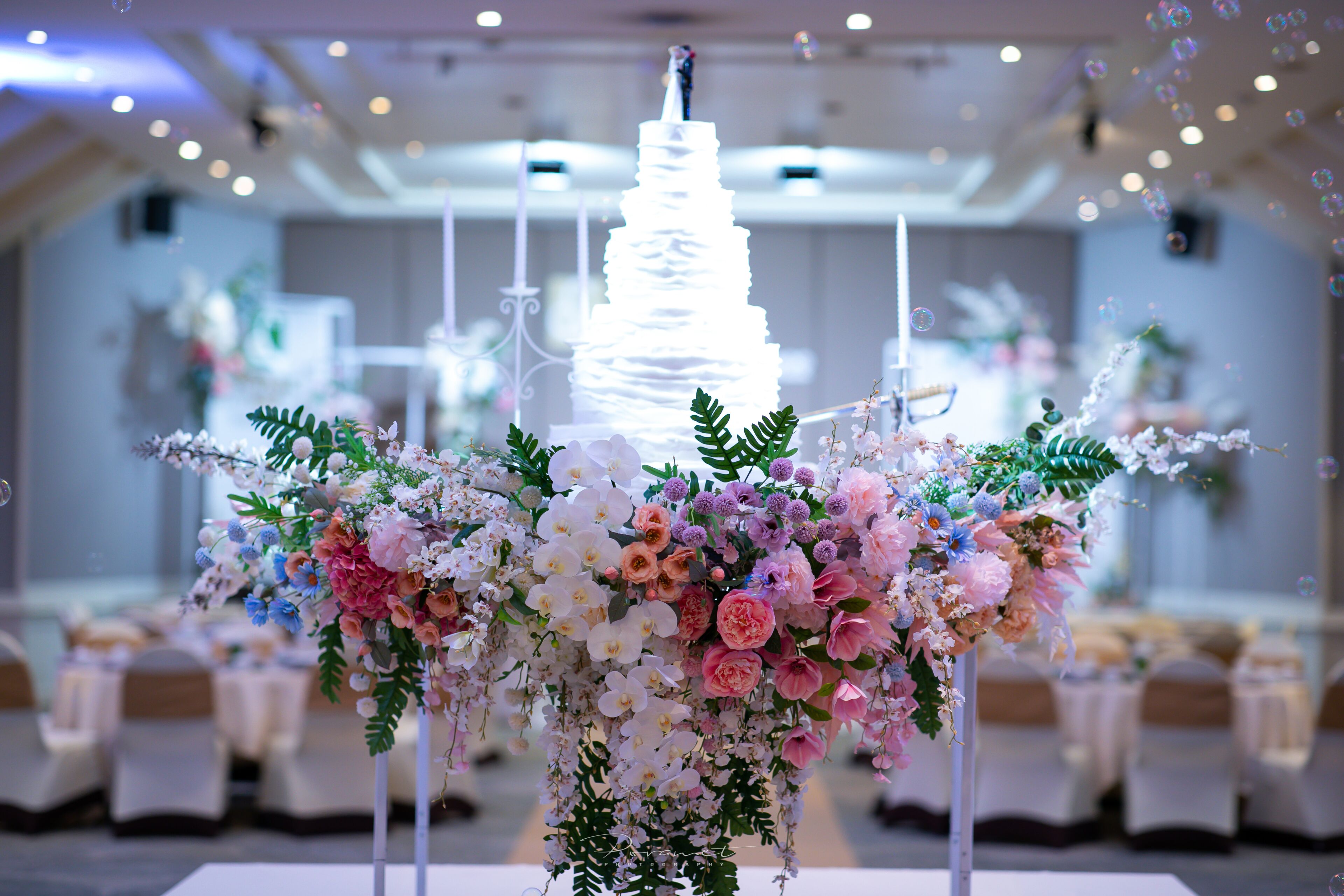 Mesa para recepción de boda con pastel de varios niveles y arreglos florales.