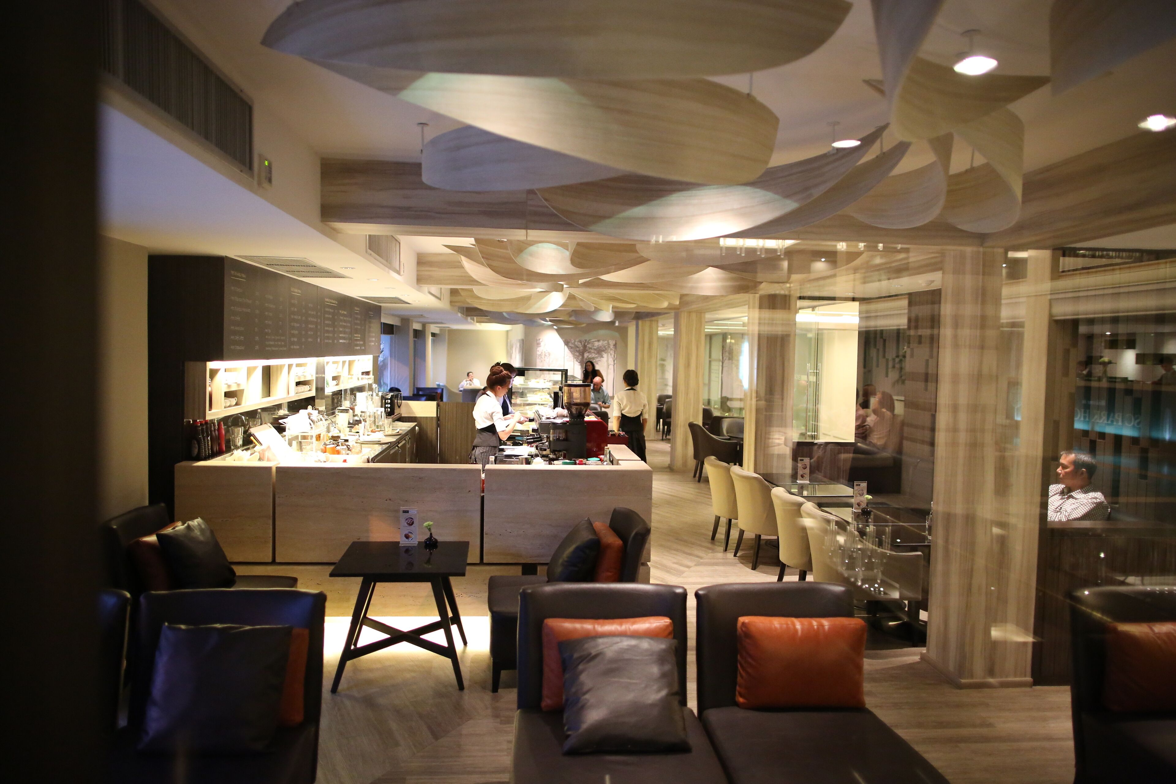 A modern hotel lobby with a bar area, seating arrangements, and a glass partition.