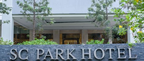 Entrada de hotel con un letrero de piedra que dice "SC PARK HOTEL".