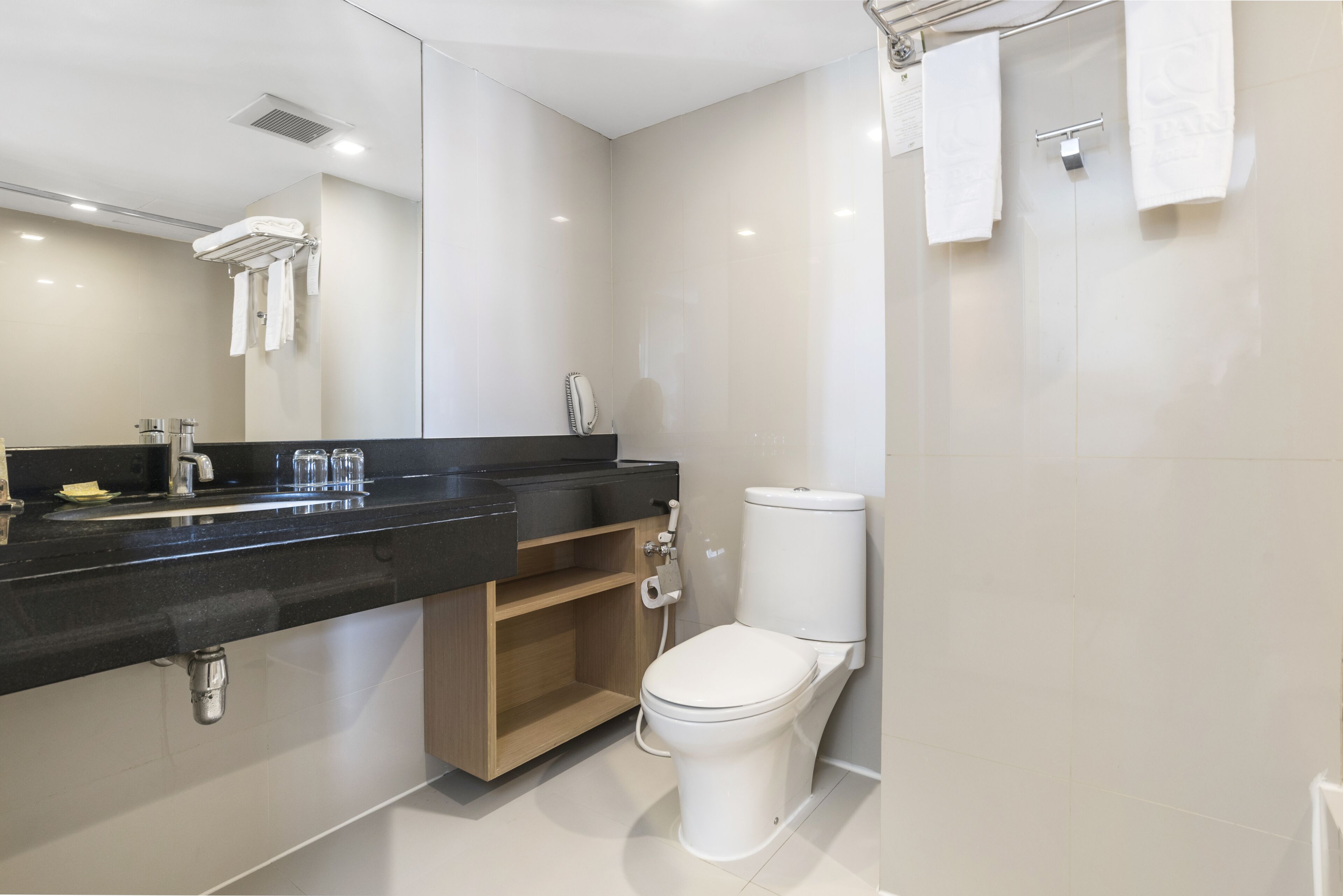 Un baño moderno con encimera negra, inodoro blanco y espejo.