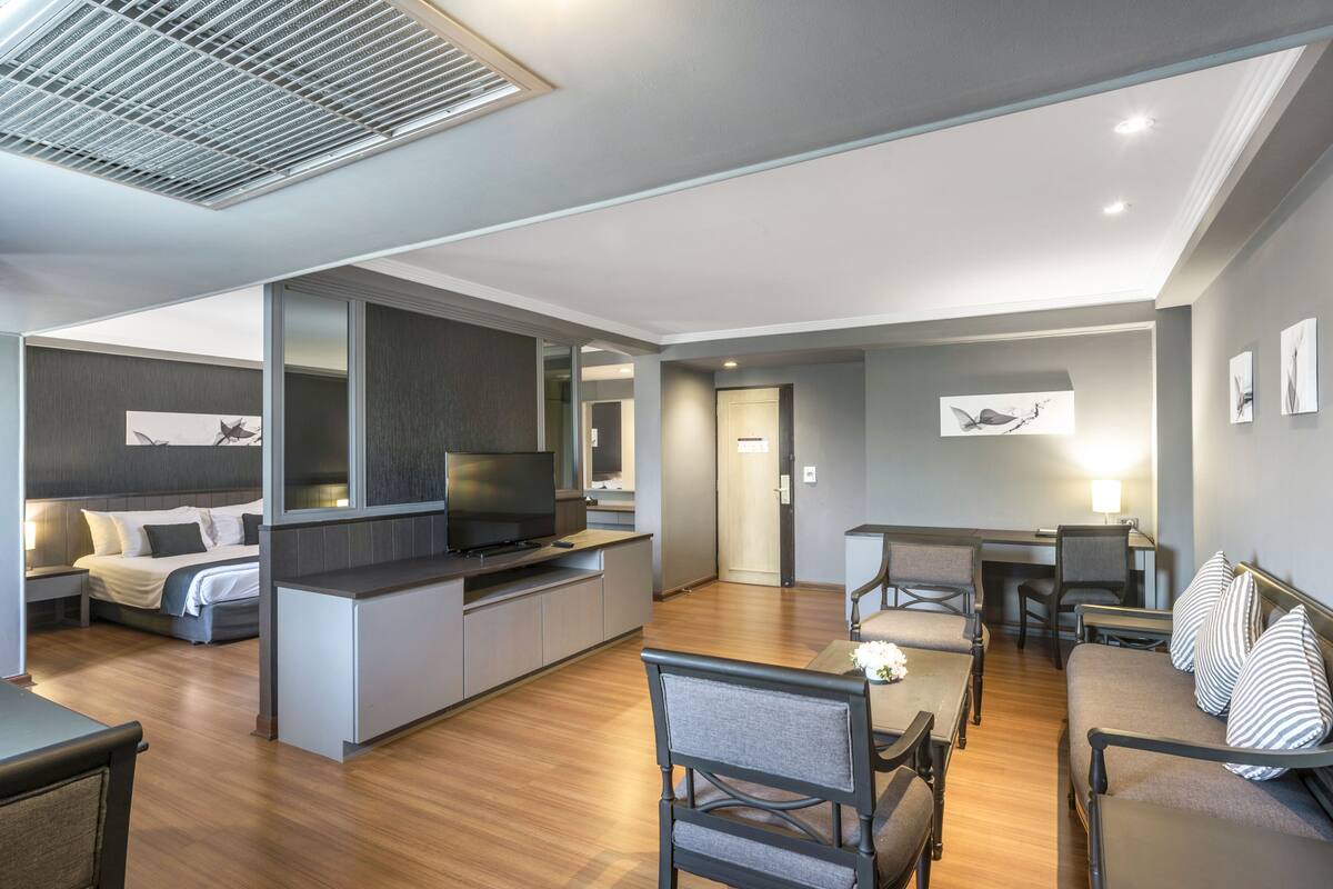 A modern living room with a flat-screen TV, a dining area, and a sofa with striped pillows.