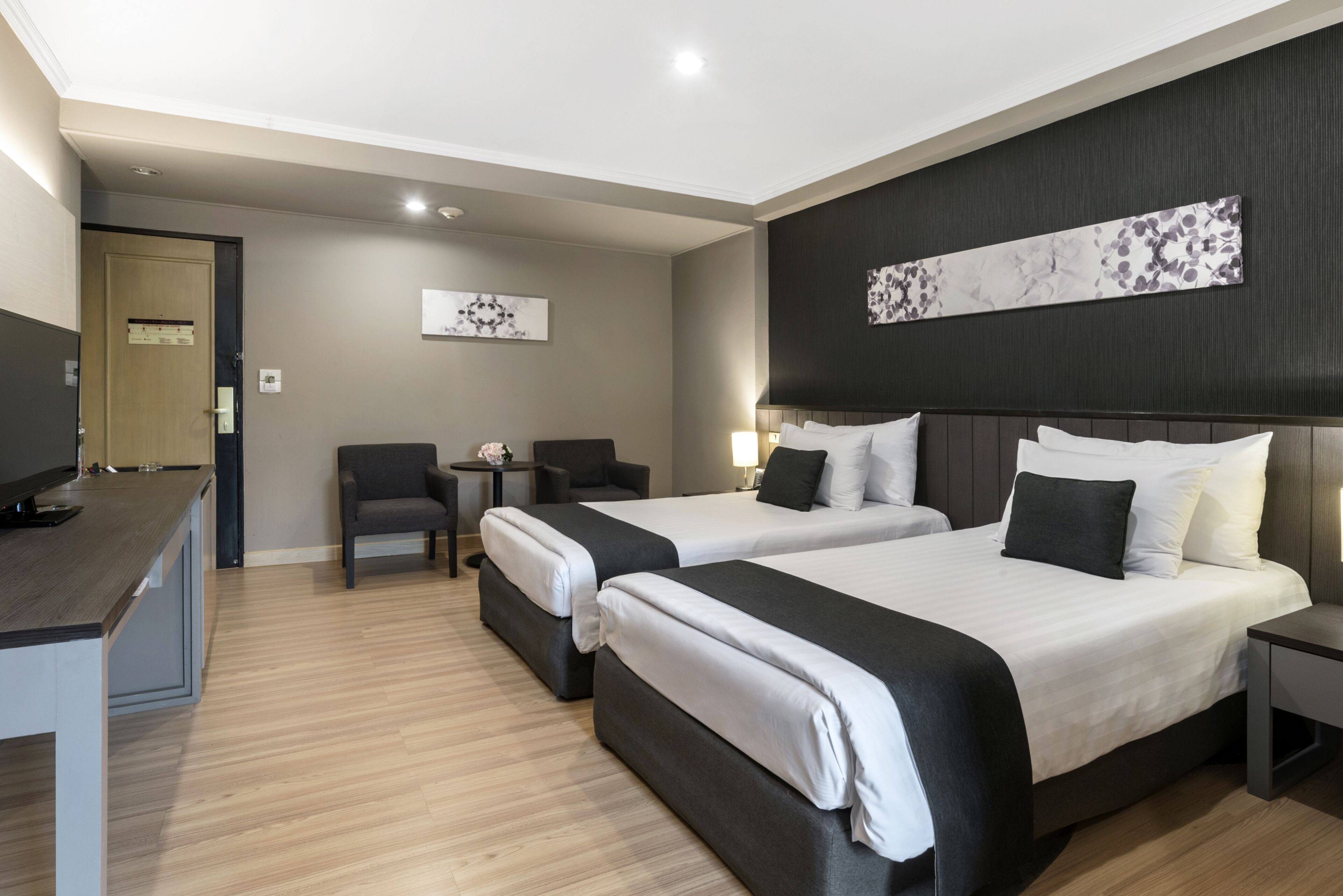 Une chambre d’hôtel avec deux lits, un bureau, une chaise et un téléviseur.