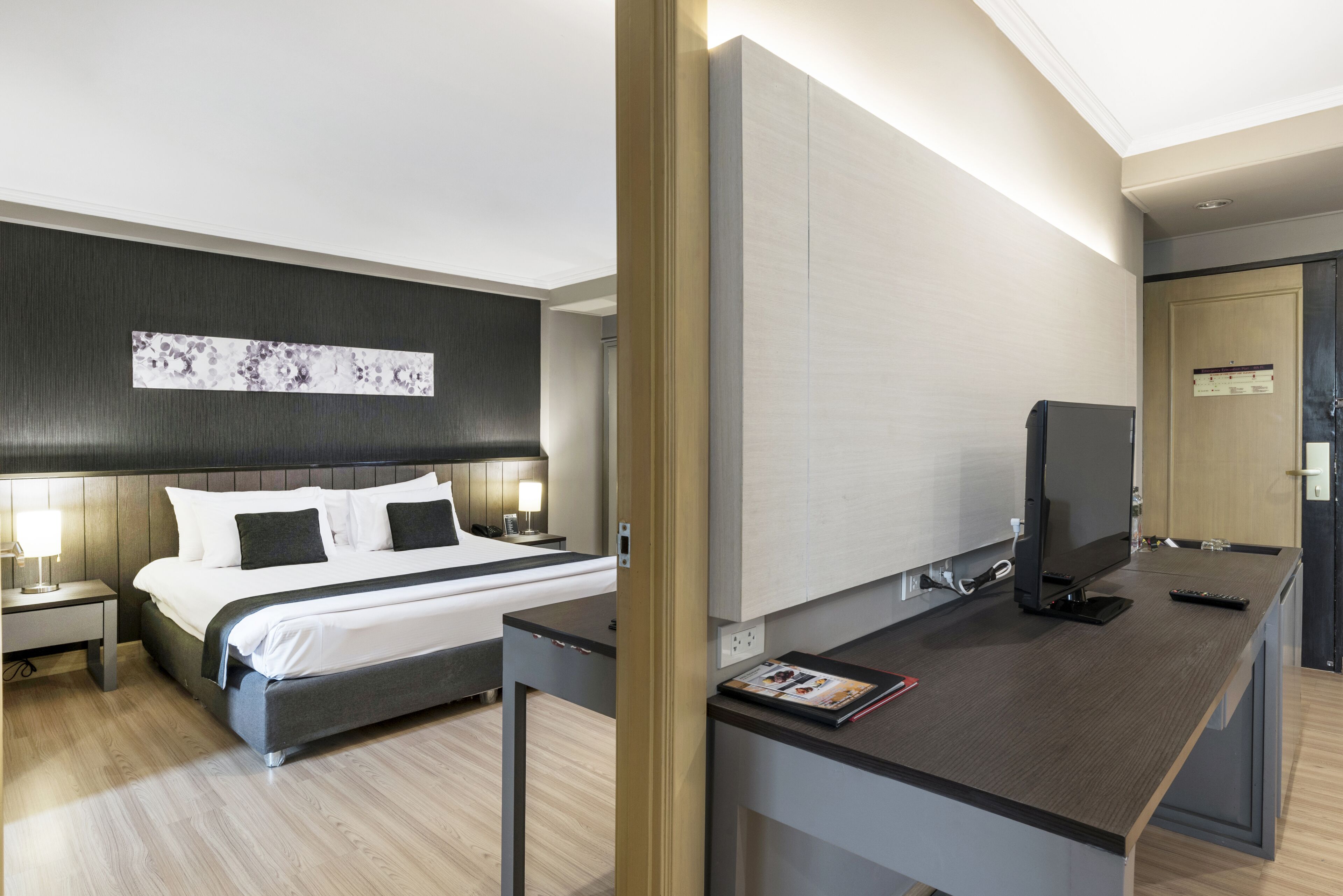 Ein modernes Hotelzimmer mit Bett, Nachttischen, einem Flachbildfernseher und einem Schreibtisch mit einer Zeitschrift.