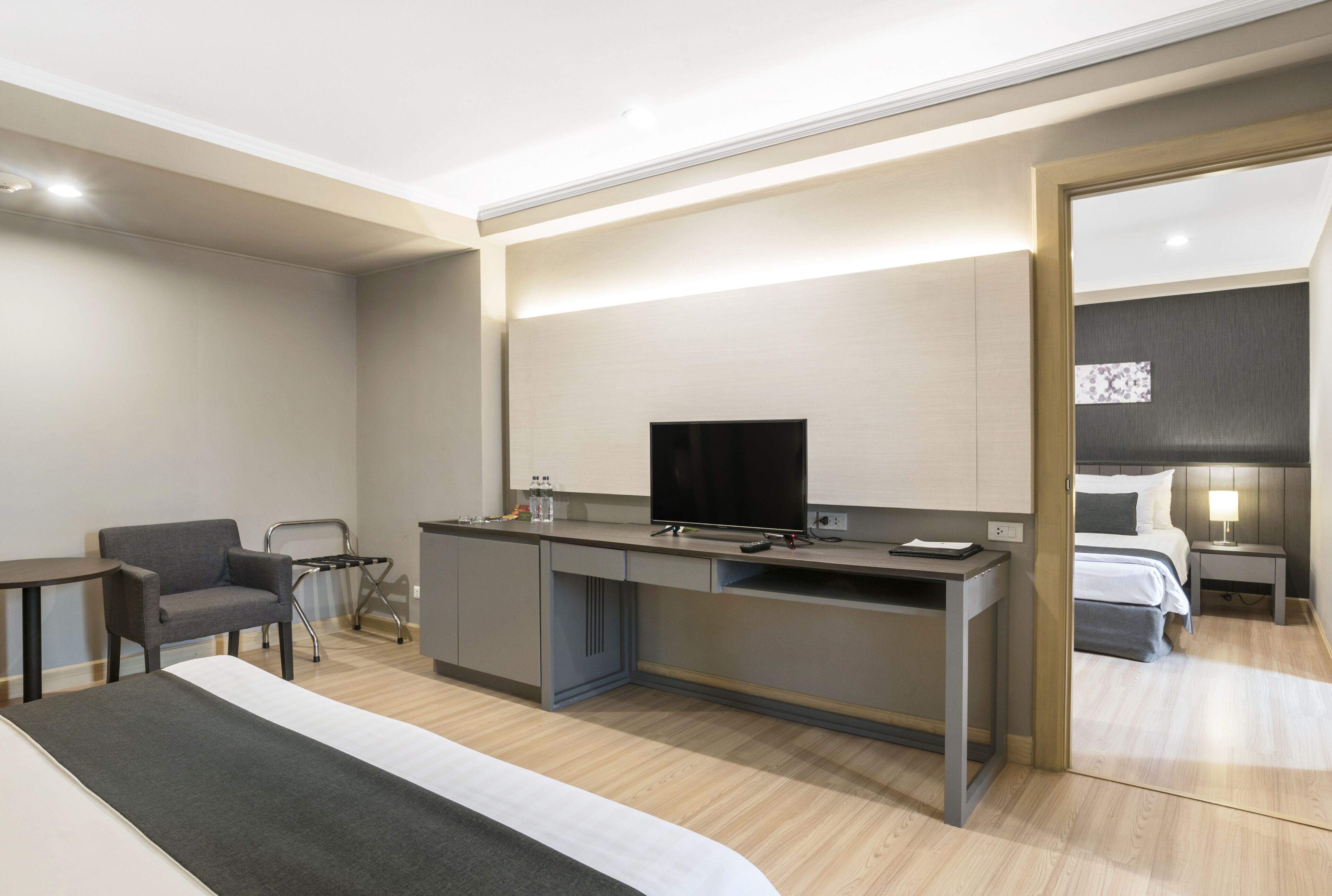 Una habitación de hotel moderna con una cama, un escritorio, una silla, un televisor y una mesita.