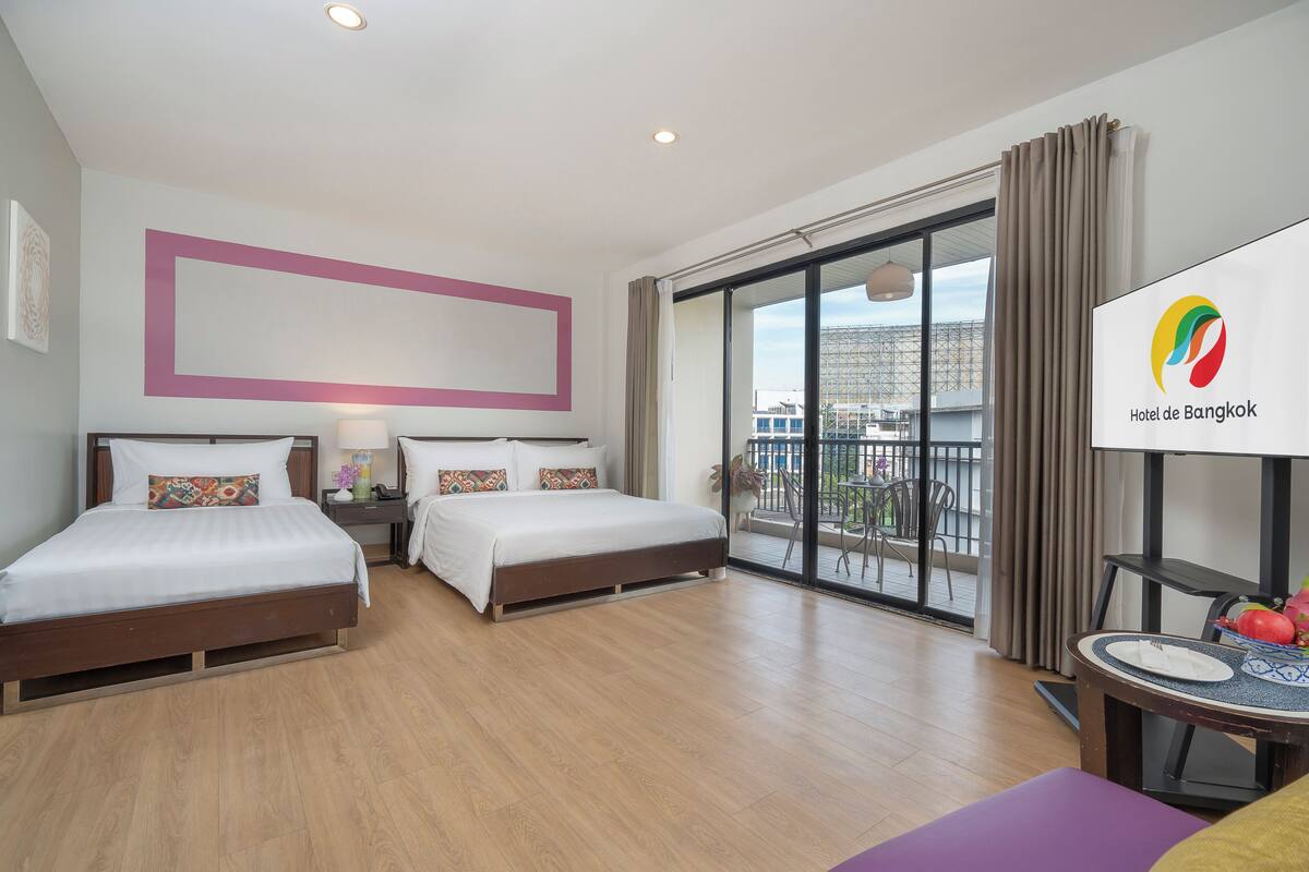Une chambre d’hôtel avec deux lits, un balcon offrant une vue sur la ville et un coin repas avec une table et des chaises.